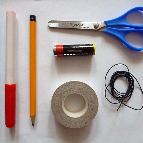 használt ceruza elem (AA vagy AAA), grafit cerka, színes filctollak (piros, kék), olló, papír, madzag